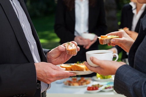 Geschäftstreffen: zwei Personen mit Sakko und Krawatte  stehen sich mit einem Imbiss in der Hand gegenüber.&nbsp;&copy;&nbsp;iStock/KatarzynaBialasiewicz