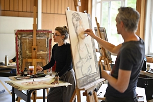 Marburger Sommerakademie Zwei Personen stehen vor Staffeleien und an Tischen und malen Bilder.