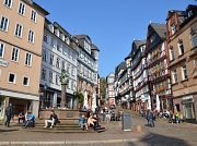 Das Bild zeigt den Blick vom Marktplatz hinauf in die Straße Markt mit Fachwerkhäusern und dem Marktbrunnen bei Sonnenschein.
