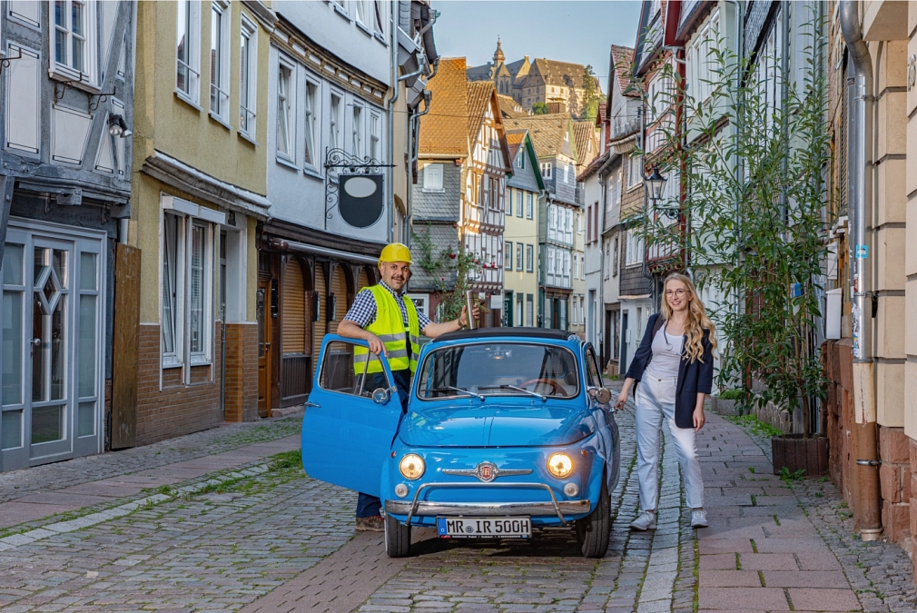 Mitfahr-App für Marburg: goMR Mitfahr-App für Marburg: Zwei Personen stehen neben einem kleinen blauen Auto. © mr//media
