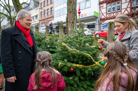 Oberbürgermeister Dr. Thomas Spies und Oberstadtmanagerin Nadine Kümmel schmücken gemeinsam mit Kindern die ersten Bäume im Weihnachtswald. © Patricia Grähling, Stadt Marburg