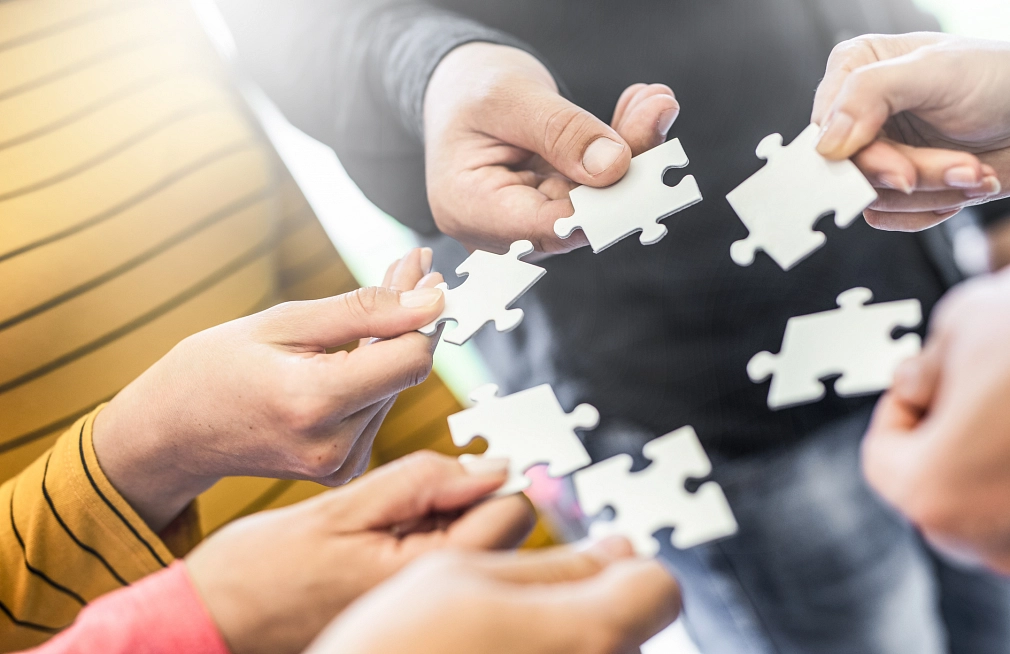 Projekt "Raus ins Leben" der Stadt Marburg, Symbolbild Hände, die Puzzleteile halten, die kreisförmig angeordnet sind. © iStock/scyther5