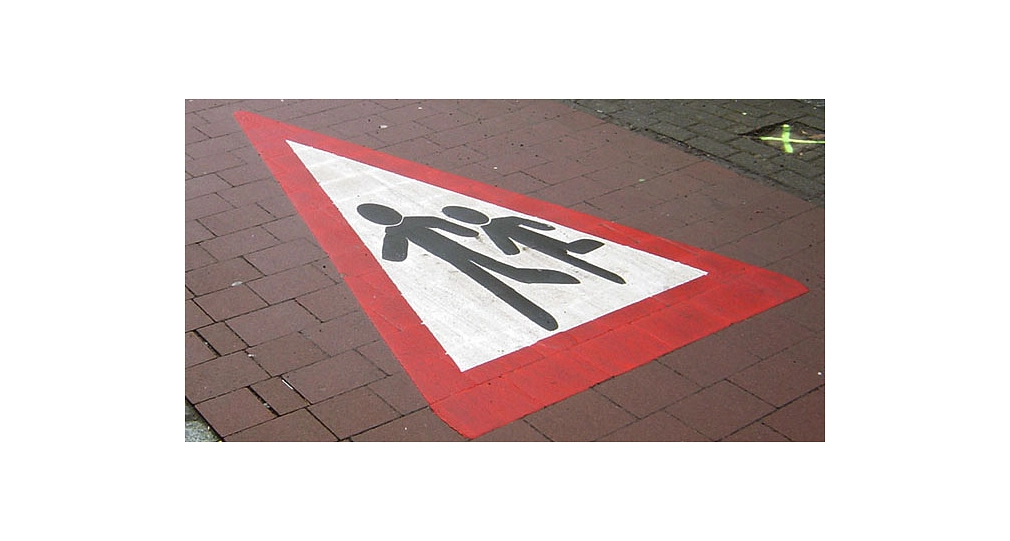Das Bild zeigt ein "Achtung Fußgänger" Schild als Markierung auf dem Radweg.
