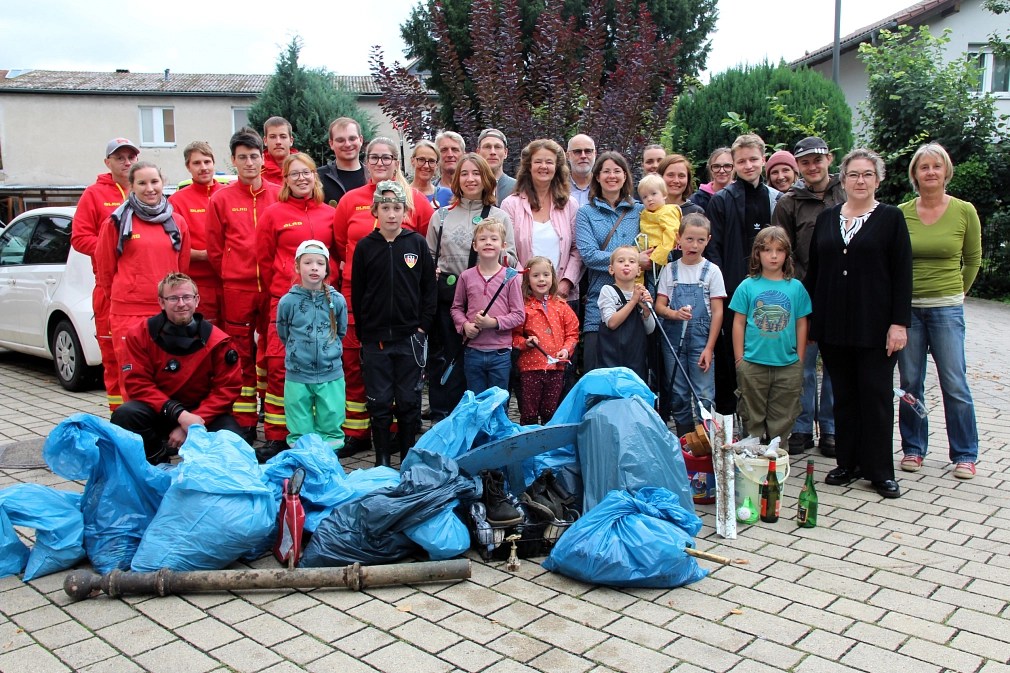 Eine Gruppe von Menschen, Kinder und Erwachsene,  steht hinter blauen, mit Müll gefüllten Säcken.