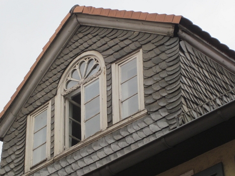 Fassade mit losen Schieferplatten und Spalten unter dem Dach. Hier könnten Fledermäuse sein.