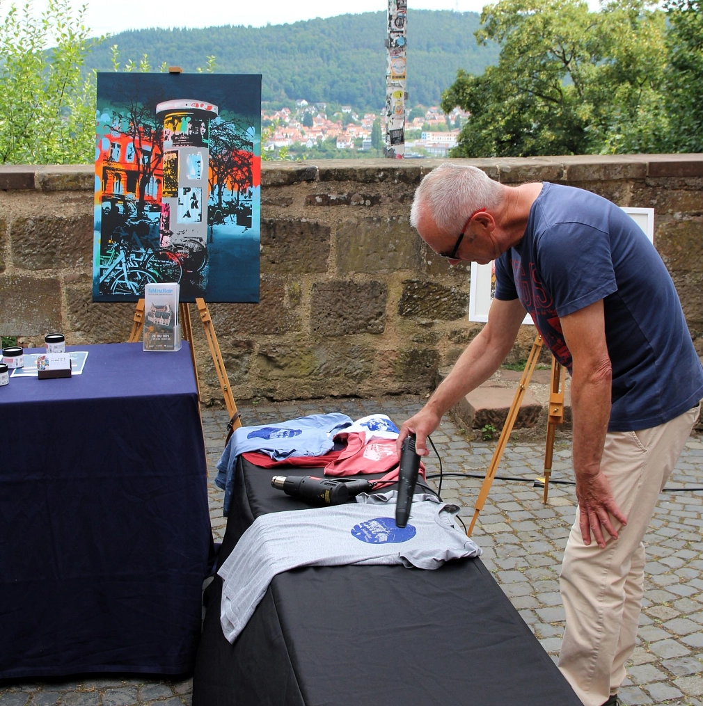 Ein Mann bearbeitet ein bedrucktes T-Shirt mit einem Heißluftföhn.