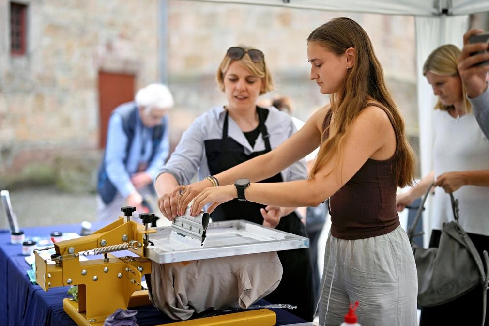 Zwei Personen machen gemeinsam einen Siebdruck.