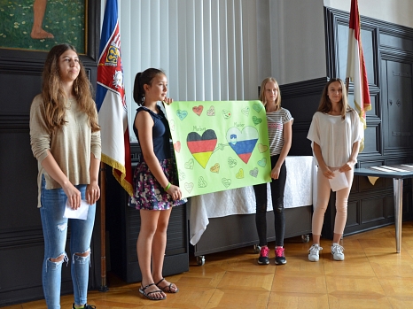 Vier Jugendliche präsentierten zwei in den Landesfarben von Deutschland und Slowenien dekorierte Herzen, die sich einig die Hand reichen. © Philipp Höhn, Stadt Marburg