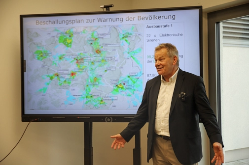 Der Oberbürgermeister steht vor dem Beschallungsplan zur Warnung der Bevölkerung.