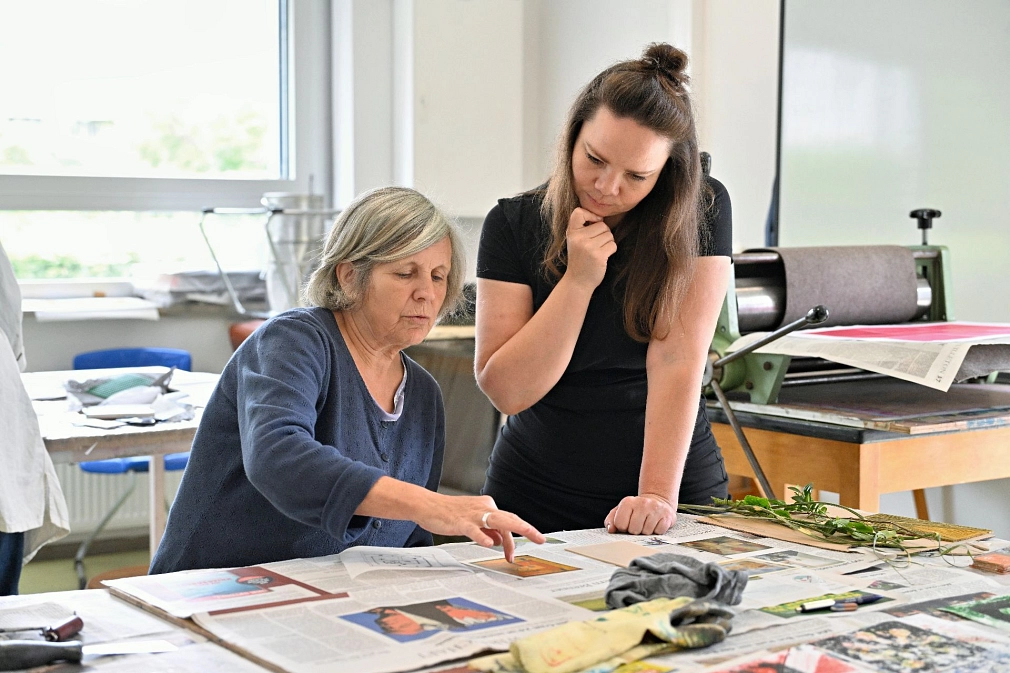 Sommerakademie: Kurs Inessa Emmer, Experimentelles Drucken Die Kursleiterin schaut einer Teilnehmerin bei der Arbeit über die Schulter. © Georg Kronenberg