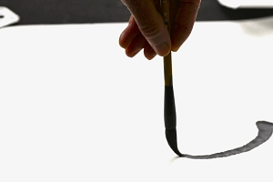 Sommerakademie: Kurs Nicole Reuther, Tuschemalerei Hand führt einen Pinsel und mal einen schwarzen Tuschestrich auf ein großes weißes Blatt.