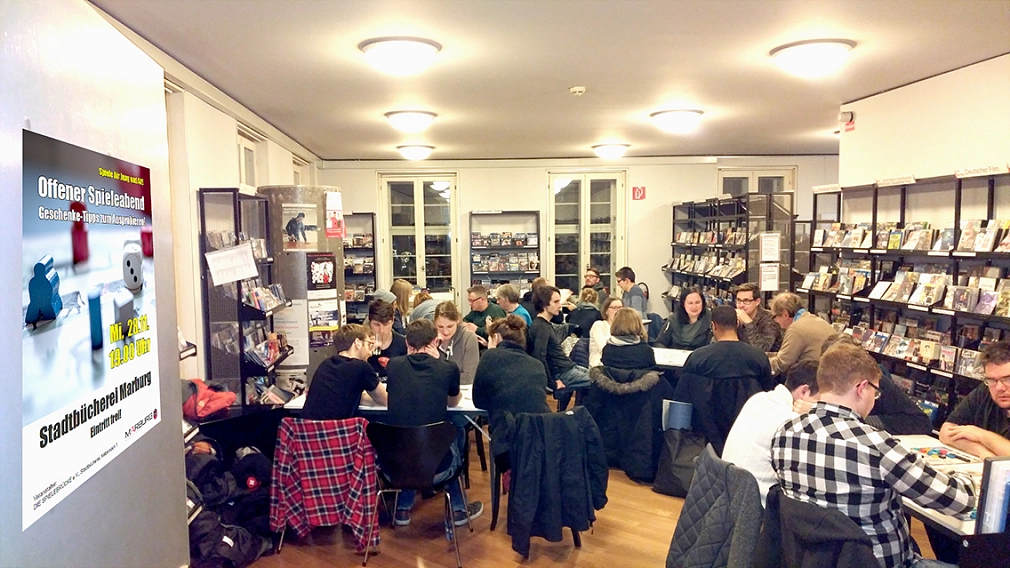 Mehrere Menschen sitzen an Tischen in der Stadtbücherei und spielen Gesellschaftsspiele.&nbsp;&copy;&nbsp;Universitätsstadt Marburg