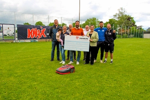 Sportförderung für FSV Cappel Menschen stehen in einer Gruppe auf einem Fußballplatz. Sie halten einen großen Scheck in der Hand.