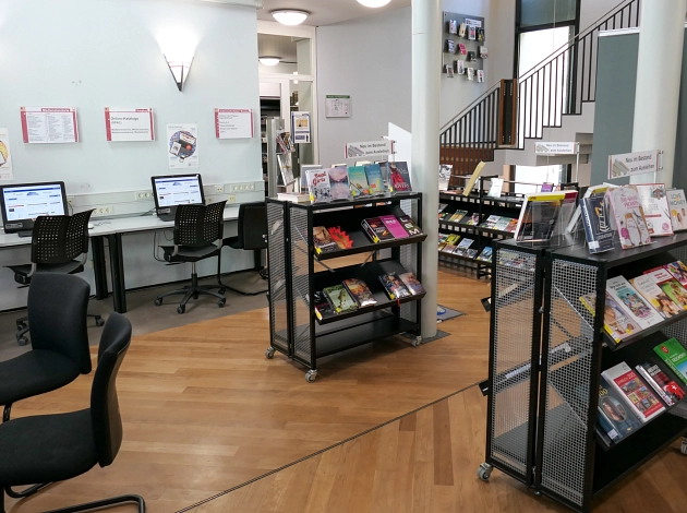 Ein Raum in der Stadtbücherei Marburg mit PC-Arbeitsplätzen und einigen Bücherregalen.