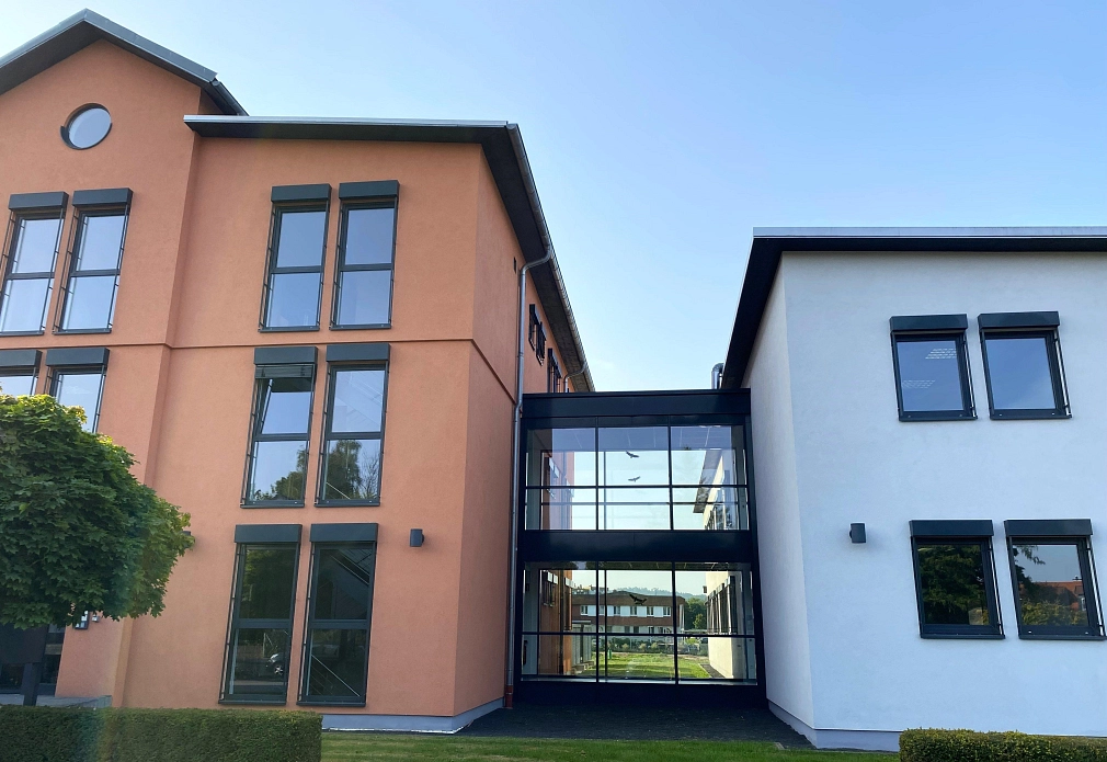 Auf dem Foto sieht man das neue Gebäude. Außerdem kann man durch eine Glasfront noch den Altbau sehen.