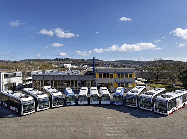 Elf Elektrobusse stehen im Halbkreis angeordnet auf einem Parkplatz der Stadtwerke Marburg.