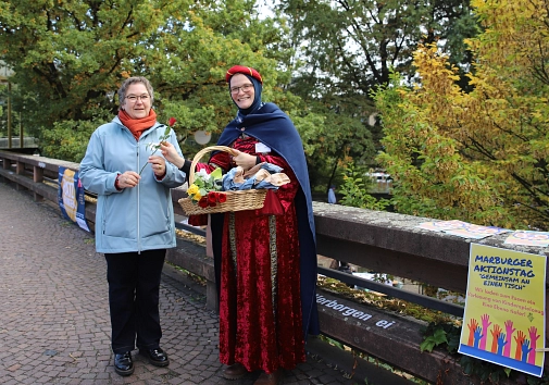 Stadträtin Kirsten Dinnebier (l.) eröffnete den Aktionstag und tauschte sich mit den Teilnehmenden und Bürger*innen aus. Citypastoral-Referentin Claudia Plociennik (r.) verteilte im Kostüm der Heiligen Elisabeth Gebäck und Rosen an Passant*innen.&nbsp;&copy;&nbsp;Lena-Johanna Schmidt, Stadt Marburg