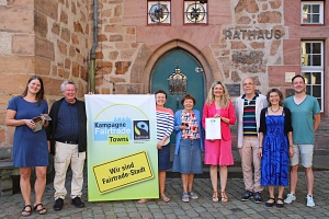 Eine Gruppe von Personen steht vor dem Rathaus mit einem Fairtrade Plakat.