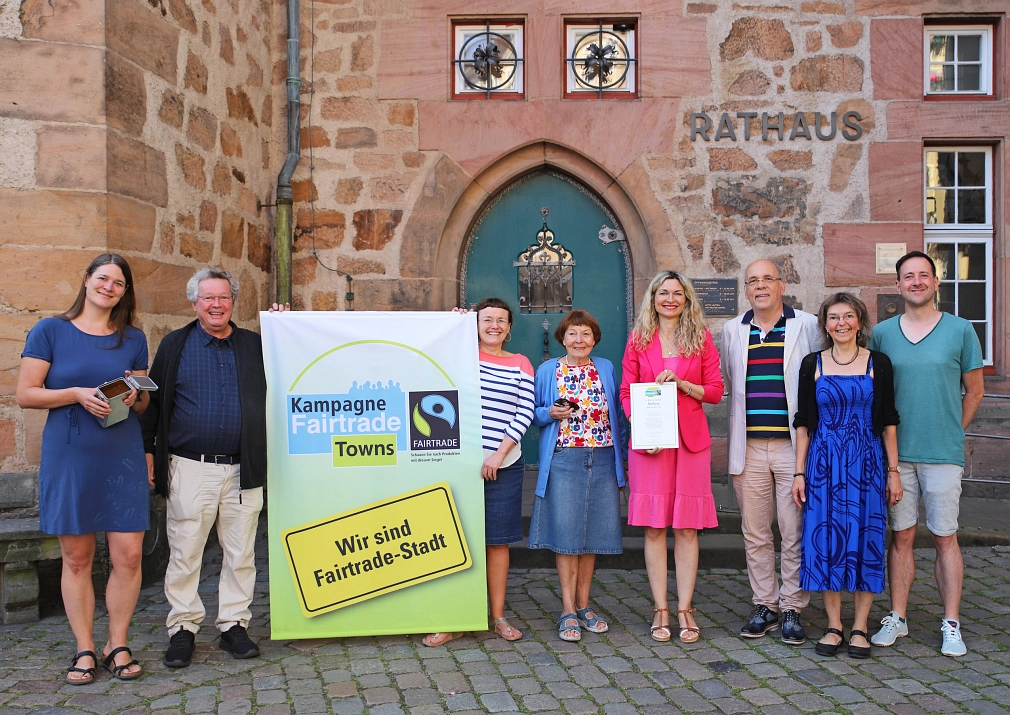 Eine Gruppe von Personen steht vor dem Rathaus mit einem Fairtrade Plakat.