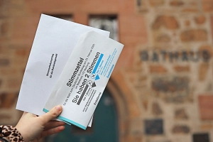 Symbolbild: Bundestagswahl 2025 Eine Frauenhand hält Stimmelzettel und Umschlag für die Bundestagswahl 2025.
