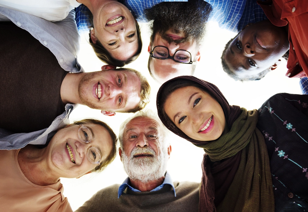 Symbolbild_Gleichberechtigung_Gruppe_iStock-871518740-Rawpixel.jpg Aufnahme von unten nach oben: eine Gruppe von Menschen unterschiedlichen Alters und Nationalitäten lächelt. © iStock/Rawpixel