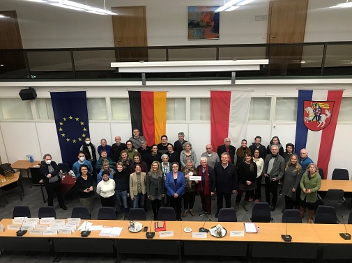 Im Stadtverordnetensitzungssaal sind ca. 30 Personen auf dem Foto abgebildet, die in die Kamera nach oben blicken.