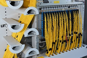 Verteilerschrank Glasfaser Ein dickes Bündel gelber Glasfaserkabel liegt in einem Verteilerschrank.