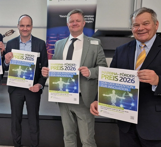 Vorschaubild MarBina-Preisausschreibung 2026 Sechs Männer stehen im Halbkreis vor einer Leinwand. Alle halten ein kleines Plakat in den Händen.