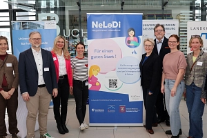 Vorstellung Neugeborenen-Lotsendienst Neun Personen stehen neben einem RollUp.