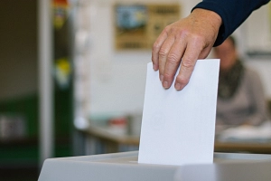 Wahlen und Wahlergebnisse Eine Person wirft einen Wahlumschlag in eine Wahlurne. Zu sehen ist nur die Hand.