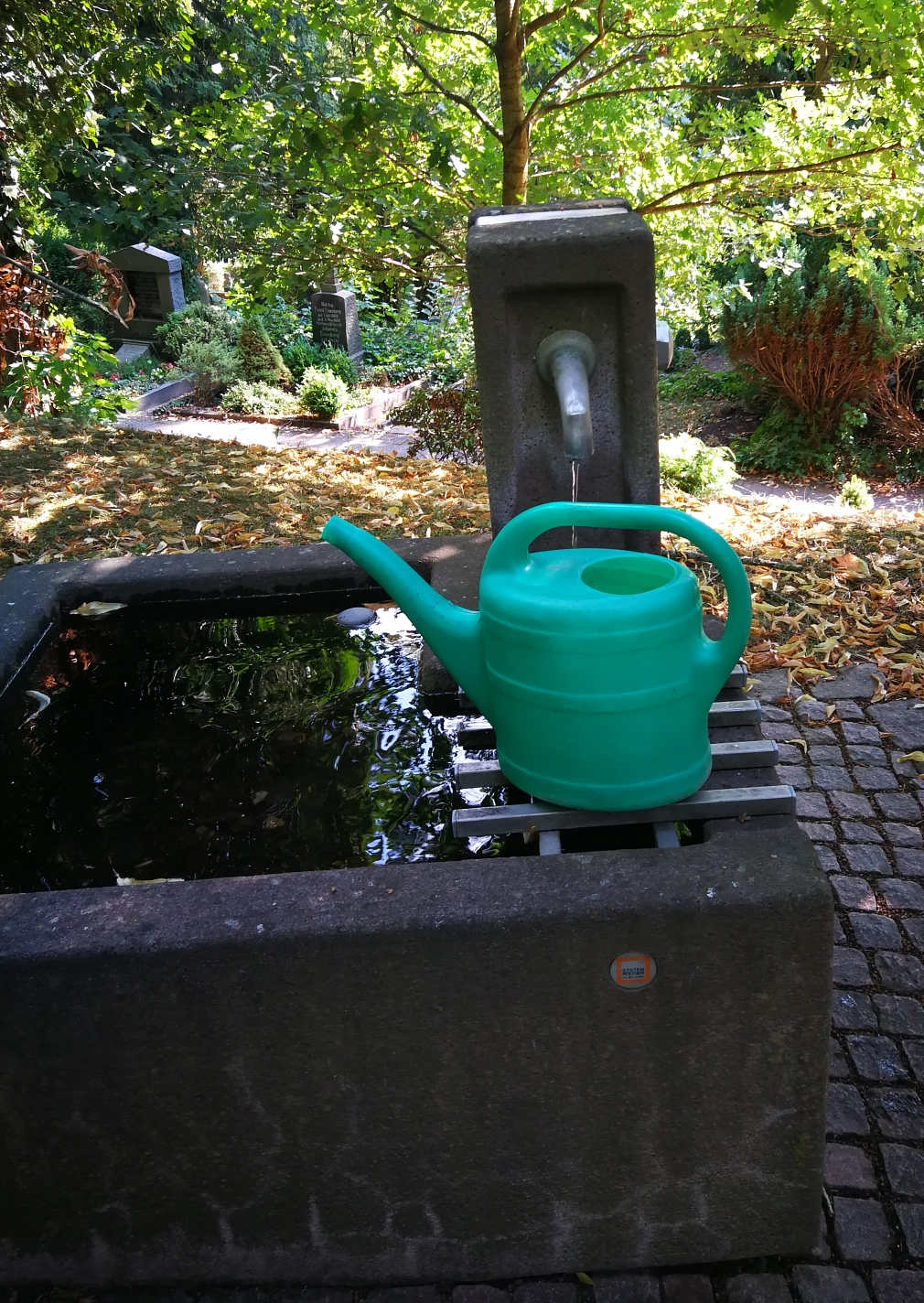 Wasserbecken auf einem Marburger Friedhof Wasserbecken auf einem Marburger Friedhof mit einer lila Gießkanne © Universitätsstadt Marburg