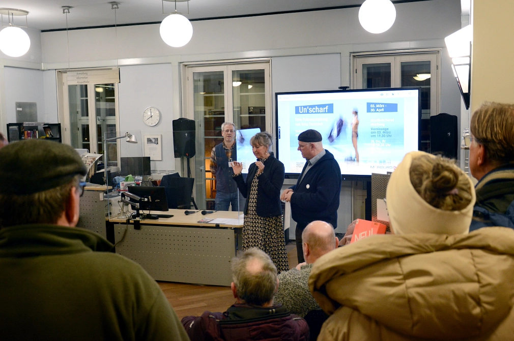 Inka Domnick (Mitte) im Werkstattgespräch mit Andreas Maria Schäfer (rechts) und Bibliotheksleiter Jürgen Hölzer (links) bei der Vernissage ihrer Ausstellung „Un’scharf“ in der Stadtbücherei.